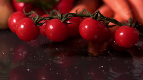 Cherry-tomatoes-falling-on-black-wet-surface