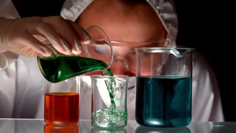 Scientist-pouring-green-liquid-into-beaker