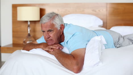 Senior-man-lying-on-bed-thinking