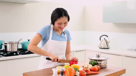 Smiling-woman-slicing-vegetables-with-a-large-knife