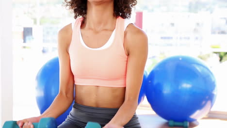 Mujer-En-Forma-Levantando-Pesas-Y-Sonriendo-A-La-Cámara