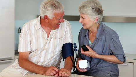 Senior-woman-taking-her-husbands-blood-pressure