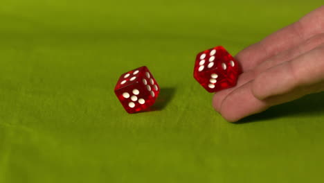 Hand-rolling-two-red-dice-on-green-table