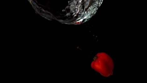 Chili-pepper-falling-in-water-on-black-background