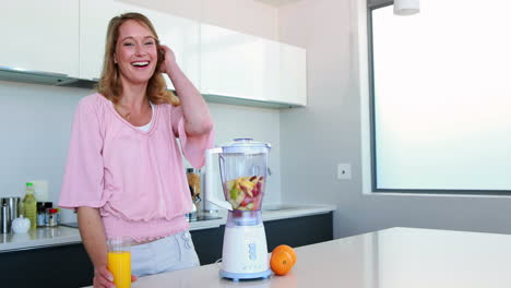 Mujer-Bonita-En-La-Cocina-Bebiendo-Jugo-De-Naranja-Al-Lado-Del-Exprimidor