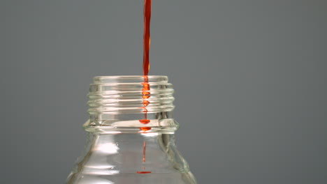 Orange-liquid-pouring-into-glass-bottle