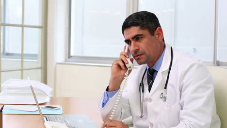 Doctor-sitting-at-desk-talking-on-the-phone