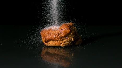 Zucker-Bestreuen-Auf-Scone-Auf-Schwarzem-Hintergrund