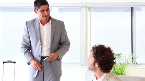 Businessman-with-a-suitcase-greeting-his-colleague