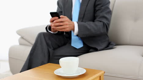 Businessman-picking-up-glasses-to-read-a-text-on-the-couch