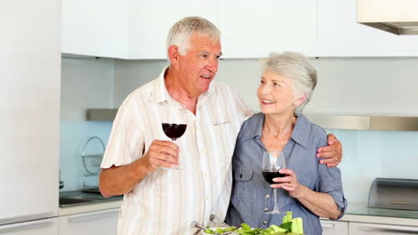 Älteres-Paar-Bereitet-Einen-Gesunden-Salat-Zu-Und-Trinkt-Dabei-Rotwein