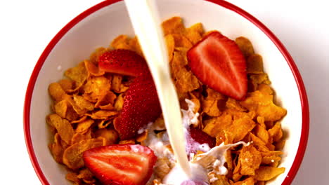 Milk-pouring-over-bowl-of-cereal-with-strawberries