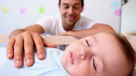 Happy-father-watching-over-baby-son-in-crib-