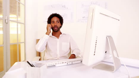 Angry-businessman-talking-on-phone-at-his-desk