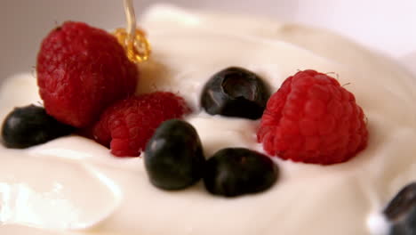 Honey-pouring-over-whipped-cream-with-berries