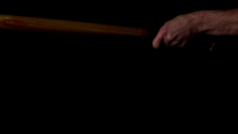 Man-hitting-baseball-with-bat-on-black-background