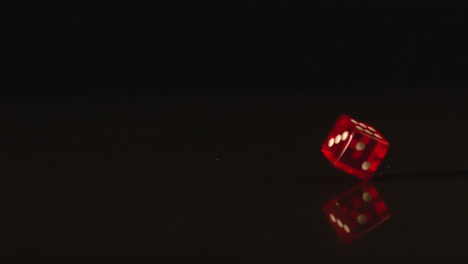 Red-plastic-dice-spinning-on-black-background