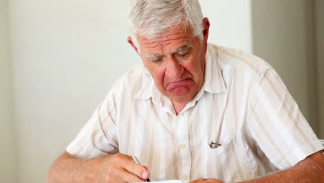 Senior-man-sitting-at-table-working-out-bills