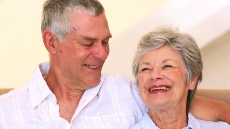 Happy-senior-couple-sitting-on-couch-chatting