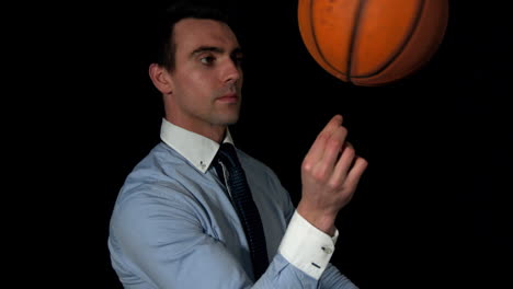 Businessman-spinning-basketball-on-finger-on-black-background