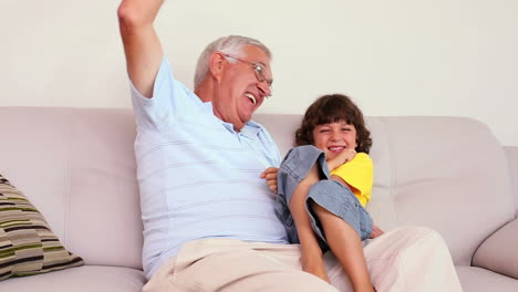 Senior-man-sitting-on-couch-with-his-grandson-