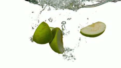 Apple-segments-plunging-into-water-on-white-background