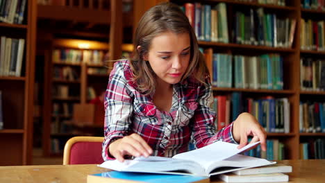 Smiling-student-studying-at-desk-in-the-library