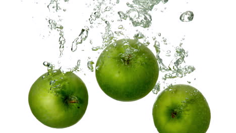 Green-apples-plunging-into-water-on-white-background