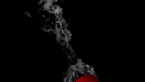 Tomate-Cayendo-En-Agua-Sobre-Fondo-Negro