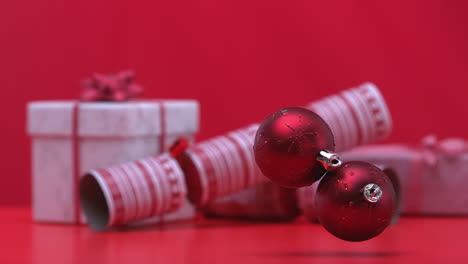 Christmas-baubles-dropping-and-bouncing-beside-crackers-and-presents