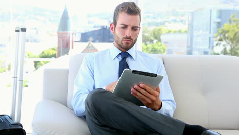 Hombre-De-Negocios-Esperando-Para-Realizar-Un-Viaje-De-Negocios-Usando-Su-Tableta