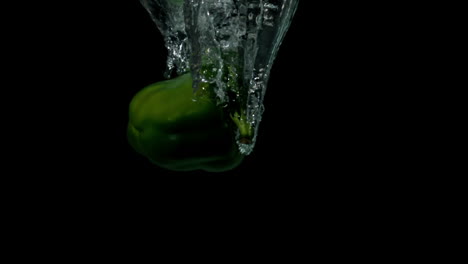 Green-pepper-falling-in-water-on-black-background