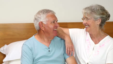Senior-couple-sitting-on-bed-chatting