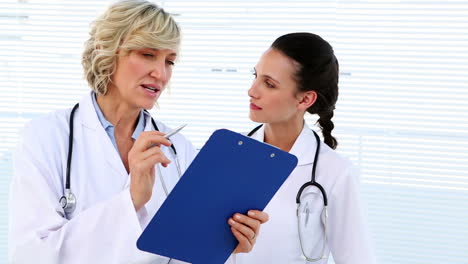 Doctor-and-nurse-discussing-something-on-clipboard