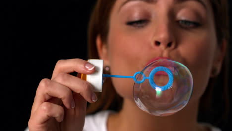 Woman-blowing-bubbles-on-black-background