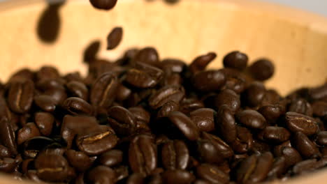 Coffee-beans-falling-into-wooden-bowl