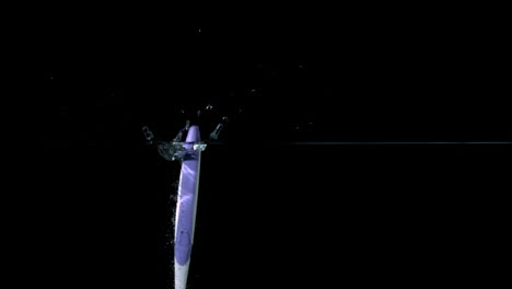 Purple-toothbrush-falling-in-water-on-black-background