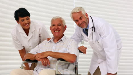 Doctor-and-nurse-talking-with-elderly-patient-in-a-wheelchair