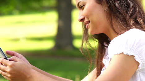 Pretty-girl-sitting-on-the-grass-sending-a-text
