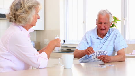 Senior-couple-sitting-at-counter-playing-cards