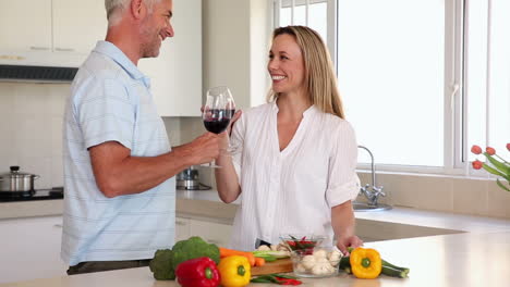 Happy-couple-drinking-red-wine-together-while-making-dinner