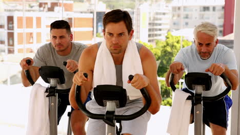 Three-men-working-out-on-exercise-bikes