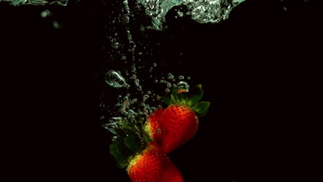 Erdbeeren-Fallen-Ins-Wasser-Auf-Schwarzem-Hintergrund