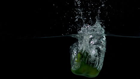 Green-pepper-falling-in-water-on-black-background