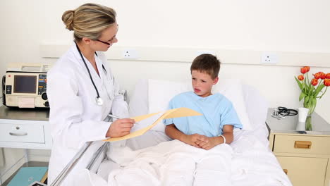 Little-sick-boy-sitting-in-bed-talking-with-doctor