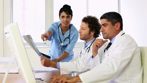 Doctors-sitting-at-desk-talking-about-xray-with-a-nurse