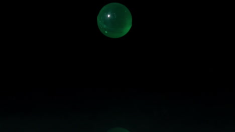 Green-marble-falling-on-black-background
