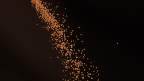 Golden-sugar-falling-against-black-background