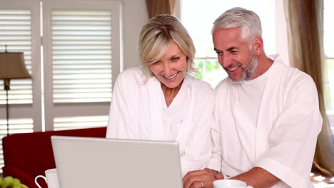 Happy-couple-using-laptop-together-in-bathrobes