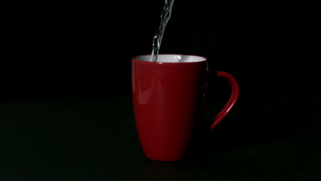 Agua-Caliente-Vertiendo-En-Una-Taza-Roja